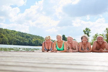 Senioren liegen entspannt auf Steg am Badesee