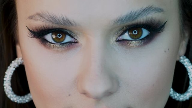 Glamorous bright eye makeup, women's eyes close-up. girl opens her eyes and looks at the camera, lush lashes and Golden eyeshadow