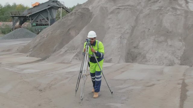 Afro industrial engineer doing land survey with tacheometer or theodolite equipment.