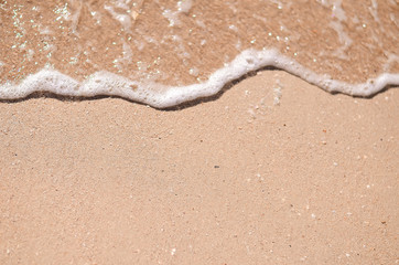 Wet sand and sea foam on the beach, sea waves. Summer time, vacation travel concept. Copy space for your text