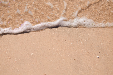 Wet sand and sea foam on the beach, sea waves. Summer time, vacation travel concept. Copy space for your text