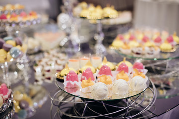 Elegant candy bar with yellow and pink cakes on the mirror table