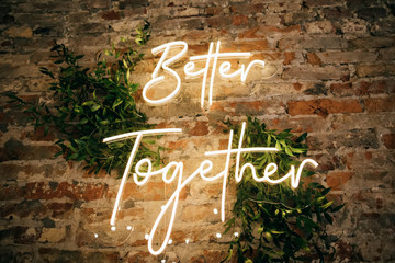 Better Together - neon sign on a brick wall in a restaurant at a wedding party. Love concept - obrazy, fototapety, plakaty