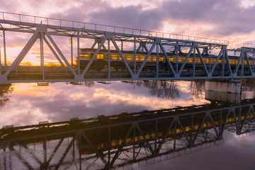 train going across bridge at sunrise