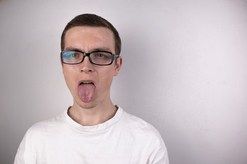 A guy in a white T-shirt on a gray background, wearing transparent glasses in a black frame, stuck...