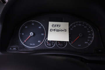 Writing zero emissions on memo post reminder. Text on sticky paper inside car dashboard.