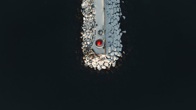 aerial photography of pier with red cap lighthouse from drone. Lofoten islands north of norway by adventure photographer roaming around winter wonderland