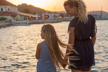 Fototapeta na wymiar Mother and the girl child in the seafront on the sunset, Hvar, Croatia