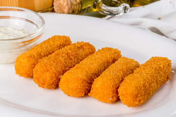 Cheese sticks on a white plate with sauce