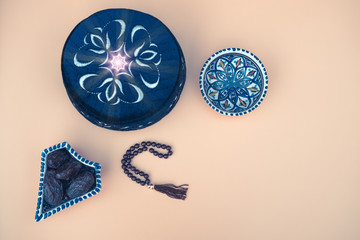 Muslim islamic faith concept taqiyah skullcap , red rosary, dates in the bowl in the Arabic style. Neutral beige background. layout and Space for text