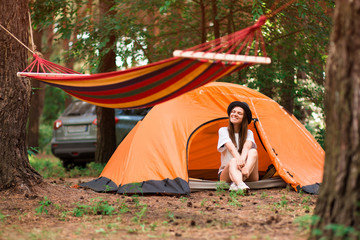 beautiful woman sitting outside tent enjoying holiday away from bustle of city in forest.