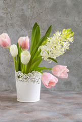 white and pink tulips and hyacinths in a white vase.