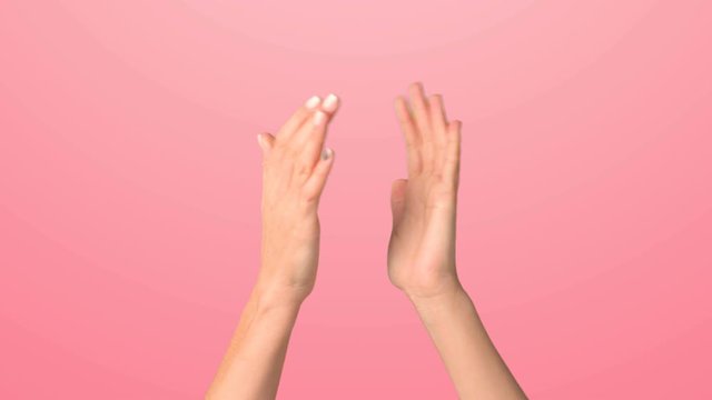 The girl raises her hands and applauds. Close up of female hands clapping on a pink background