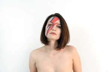 red and blue lightning bolt on her beautiful face. Beautiful girl with original make-up on a white...