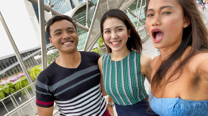 Three asian friends enjoying outdoor city life, taking selfies. Friendship and holiday concept