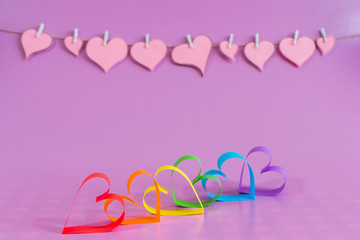 Love hearts with the colors of LGBT on pink background.