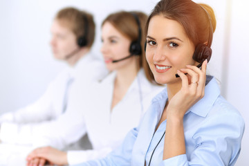 Fototapeta premium Call center. Focus on beautiful business woman using headset in sunny office