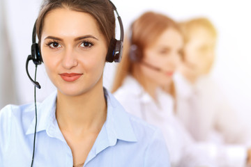 Call center. Focus on beautiful business woman using headset in sunny office