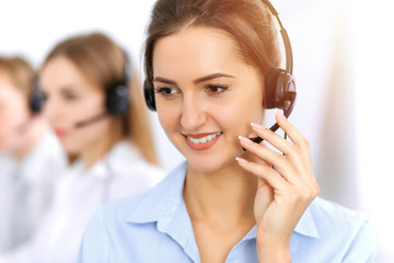 Call center. Focus on beautiful business woman using headset in sunny office