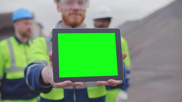 Industrial engineers in safety uniform and hardhats with digital tablet on construction site