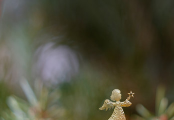 Christmas card with a golden angel in front of a green background with colourful christmas reflections