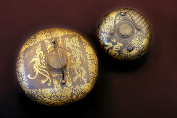 Two ancient asian pots with dragon symbols and eastern signs and hieroglyphs, both are of round shape. Objects on dark background, close up, copy space.