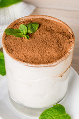 Tiramisu dessert in a white glass with mint leaves