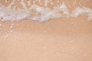 Wet sand and sea foam on the beach, sea waves. Summer time, vacation travel concept. Copy space for your text