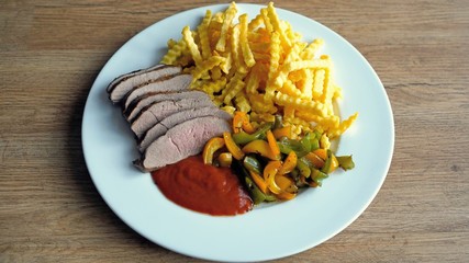 roasted fillet from red deer calf with french fries and yellow and green paprika