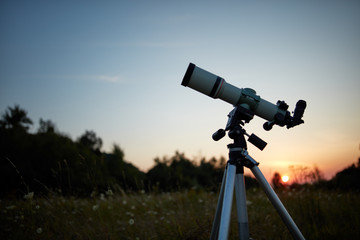 Telescope for observing the universe on a meadow outdoors.