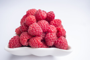 Raspberry berries close-up. fresh raspberries in a white cup on a white background. Side view. Soft focus.