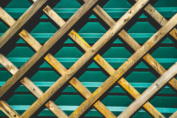 Wooden grating in front of an iron green fence. Pattern background