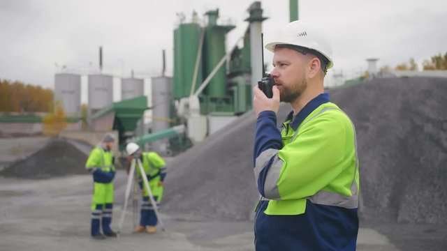 Caucasian mine worker in safety wear with walkie-talkie at mining site