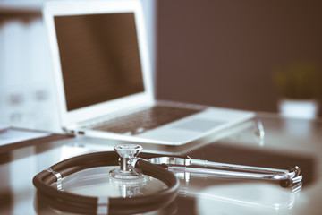 Stethoscope, prescription medical form lying on glass table with laptop computer. Medicine or pharmacy concept. Medical tools at doctor working table