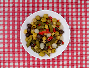 pickled vegetables on a white plate over a red and white checkered tablecloth