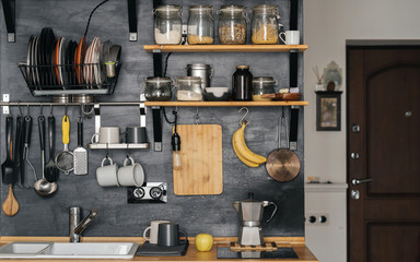 The design of modern home cooking is made in the style of loft and rustic. black wall with shelves, coffee maker, jars, mugs, sink and fruit.