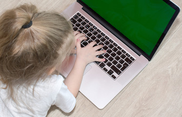 Fototapeta premium Happy little girl at home working with a laptop green screen