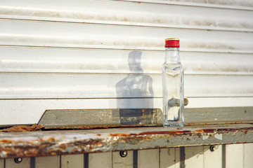 alcoholism problem concept picture of empty vodka bottle on dirty windowsill white kiosk background plastic view slum ghetto urban city street environment, copy space for your text here