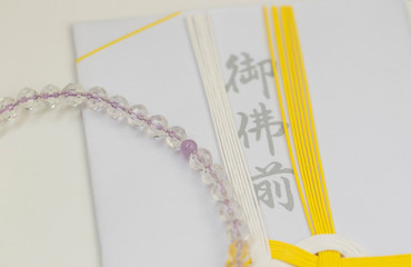 日本の香典袋（特に関西地方で使われる黄色と白色の水引）と数珠