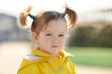portrait of a little cute girl of Asian appearance 3 years with red hair in a yellow cloak