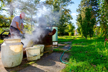 Man is empty fruit marc from distillation apparatus after cooking and making domestic alcohol liquor