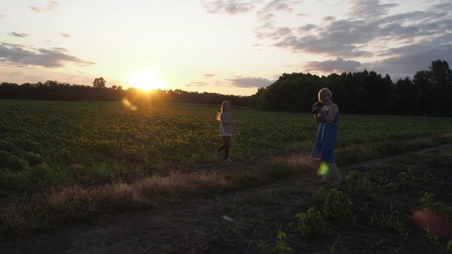 Photographer a woman photographs a teenage girl in a field at sunset