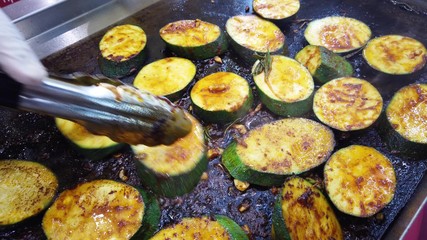 Roasting round slices of zucchini, vegetarian cuisine. The cook flips the fried slices to the other side.