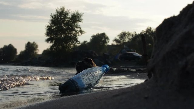 a plastic bottle is lying on the beach. Waves wash over it. Concept of combating environmental pollution