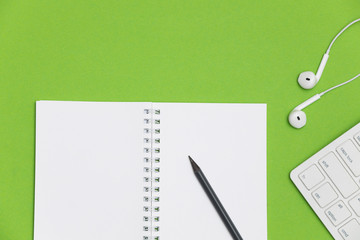 Minimal workplace with blank notepad, keyboard and supplies on colored background. Top view. Flat lay