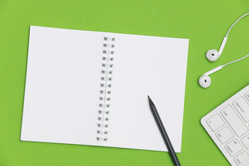 Blank spiral notebook and pencil on green background. Top view with copy space for input the text.	