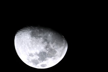 Close up, zoomed in shot of a gibbous moon in dark skies background