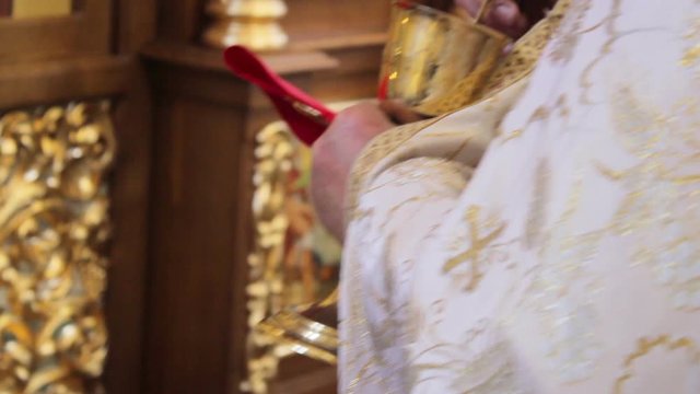 priest holds the Chalice,priest rite of holy communion in church with cup of bread and wine, communion with spoon