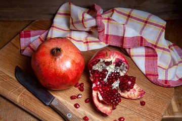 Fresh red pomegranate with vintage knife on a wooden background..