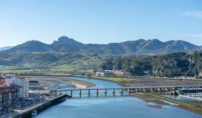 Fototapeta na wymiar Aerial view landscape of Ribadesella port town, in Principado de Asturias, Spain. The centered bridge crossing the Sella river and mountains in the background.